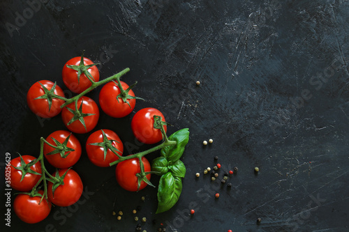 Fresh tomatoes on a black background with spices. Top view