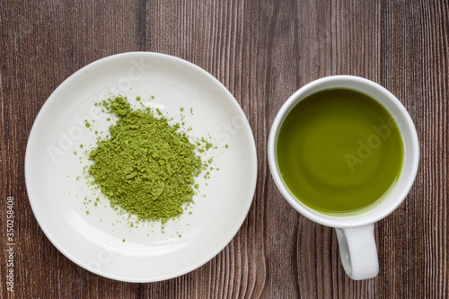 cup of matcha tea and matcha green tea powder in bowl on wooden table. Top view. healthy food concept
