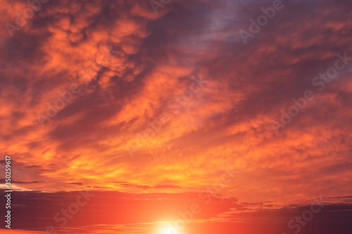 Epic dramatic sunset, sunrise red orange sky with mammatus clouds, sun and sunlight