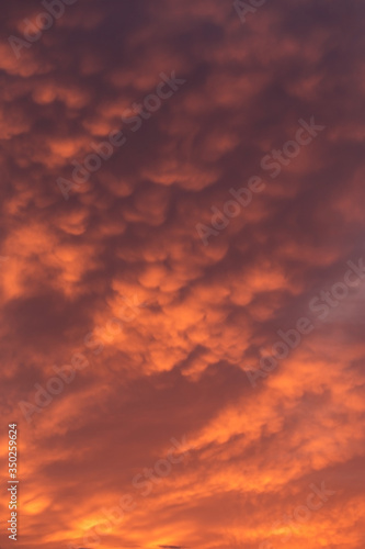 Dramatic sunrise, sunset red orange sky with mammatus clouds background texture