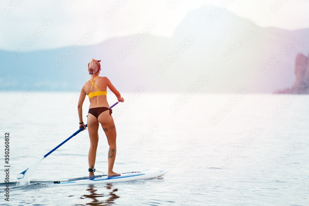 Naklejka premium Sports girl on a board for glanders surfing in the sea