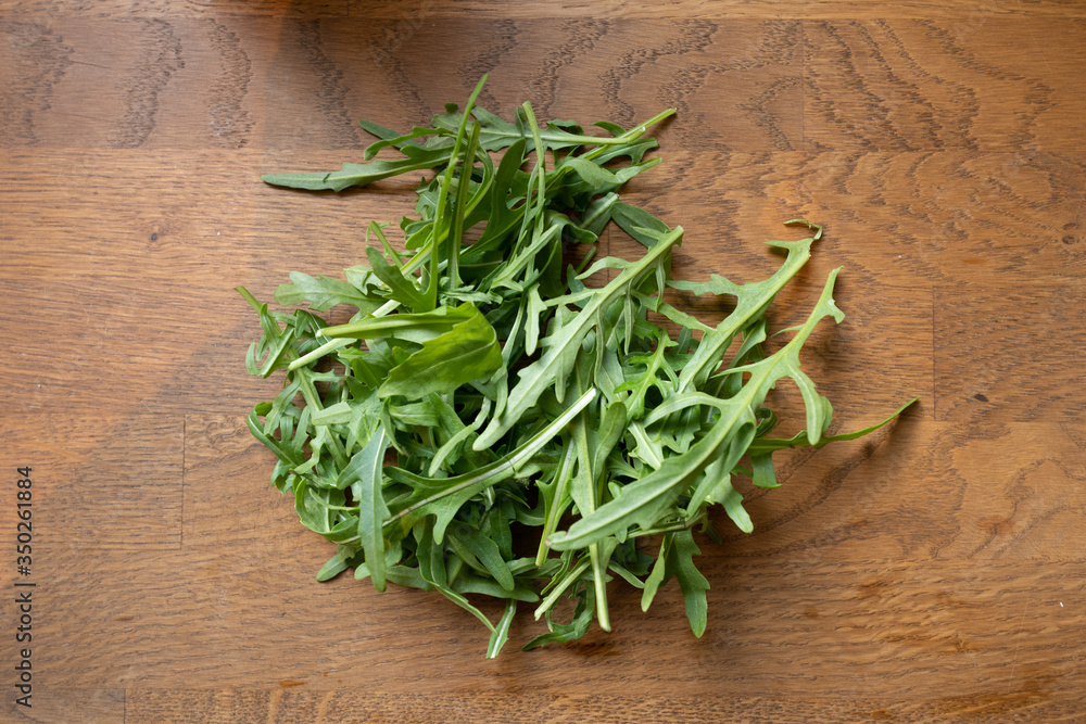 Rucola laying on table, flatlay shot from above, brown kitchen table Rucola laying on table, flatlay shot from above, brown kitchen table
