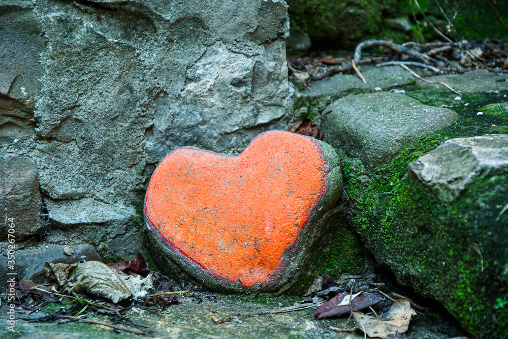 Close-up of a heart-shaped red painted stone in the corner of a gray stone alley, Italy Close-up of a heart-shaped red painted stone in the corner of a gray stone alley, Italy