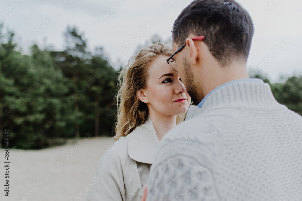 Fototapeta premium Young woman and man hug and kiss in a sand quarry.