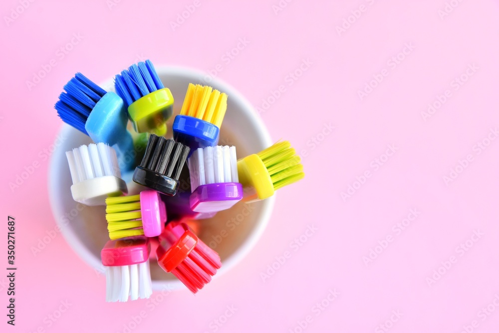 Colorful new plastic toothbrushes in white mug on pink neutral background, top view, selective focus, copy space. Trendy health care concept Colorful new plastic toothbrushes in white mug on pink neutral background, top view, selective focus, copy space. Trendy health care concept