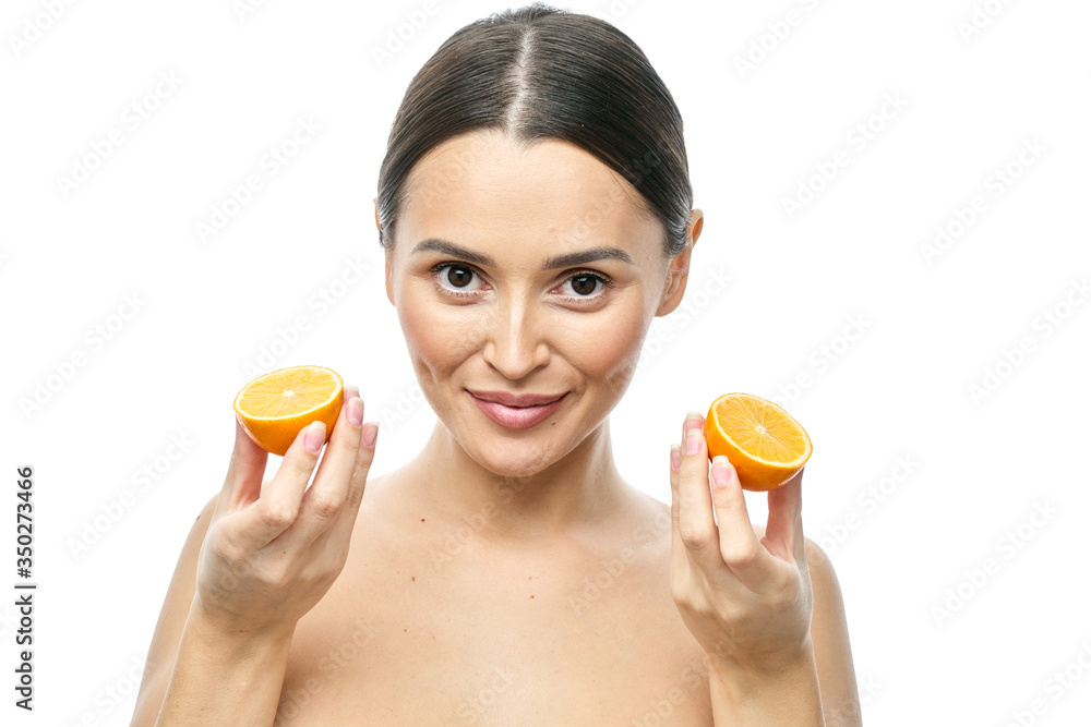 Close up beauty portrait of an excited attractive half naked woman holding Meyer lemon slices at her face and looking at camera isolated over white background Close up beauty portrait of an excited attractive half naked woman holding Meyer lemon slices at her face and looking at camera isolated over white background
