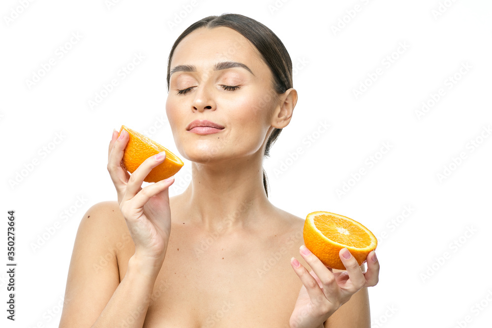Close up beauty portrait of an excited attractive half naked woman holding orange slices at her face and looking at camera isolated over white background Close up beauty portrait of an excited attractive half naked woman holding orange slices at her face and looking at camera isolated over white background