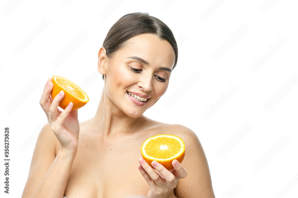 Close up beauty portrait of an excited attractive half naked woman holding orange slices at her face and looking at camera isolated over white background