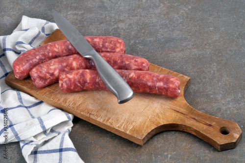 Raw sausages with a knife on a cutting board