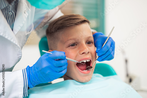 Cute little boy sitting on dental chair and having dental treatment.