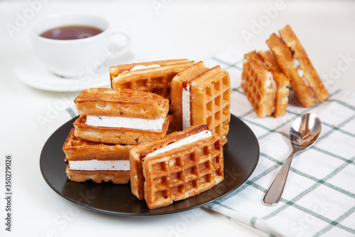 Belgian waffles and tea in a mug on the table.