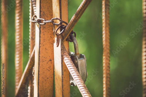 A large closed lock with a chain hangs on an iron gate. The concept of restrictions, prohibitions, closed space, quarantine. photo