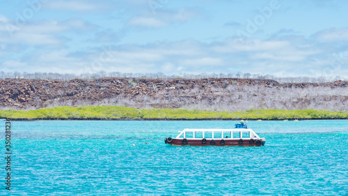 The channel between Baltra island and Santa Cruz island (Galapagos, Ecuador). On the turqoise waters a vessel is sailing photo