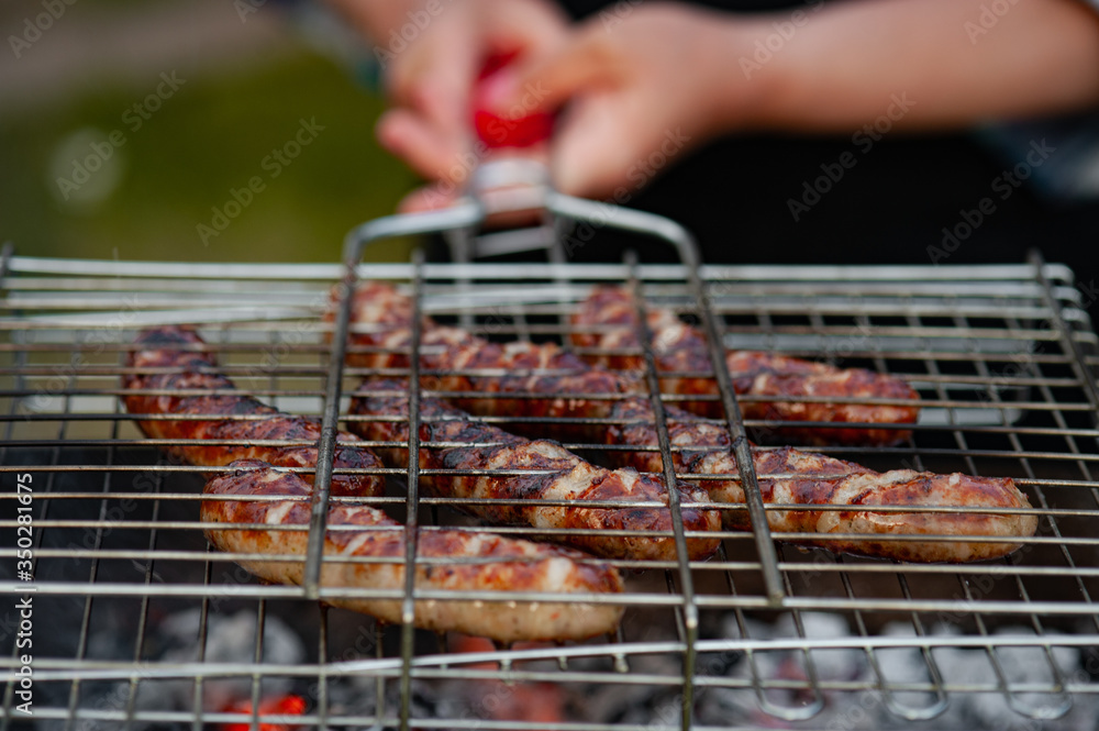 Hot sausage grilling outdoors on a barbecue grill.