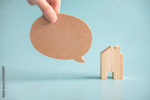 Talk bubble speech icon. Hand holding blank empty bubbles design elements with wood home on blue background. Chat symbol. copy space.