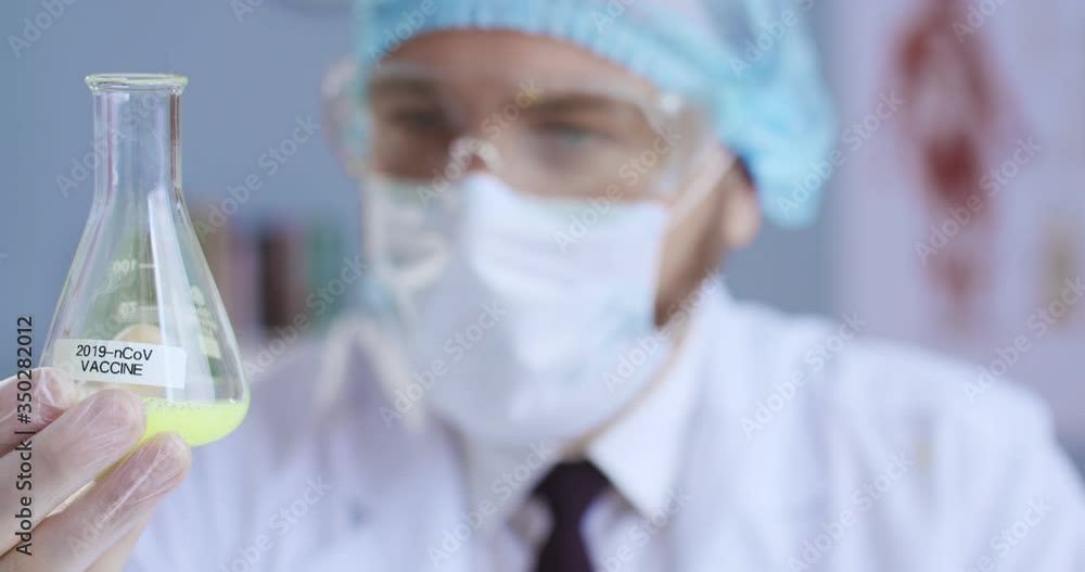 Close-up portrait of scientist working with chemical reaction in chemistry lab. Chemical reaction in glass flask. Lab worker doing chemical experiment in laboratory. Сoncept pandemic, modern medicine. Close-up portrait of scientist working with chemical reaction in chemistry lab. Chemical reaction in glass flask. Lab worker doing chemical experiment in laboratory. Сoncept pandemic, modern medicine.