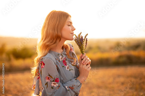 Young woman enjoying smell of flowers in evening photo