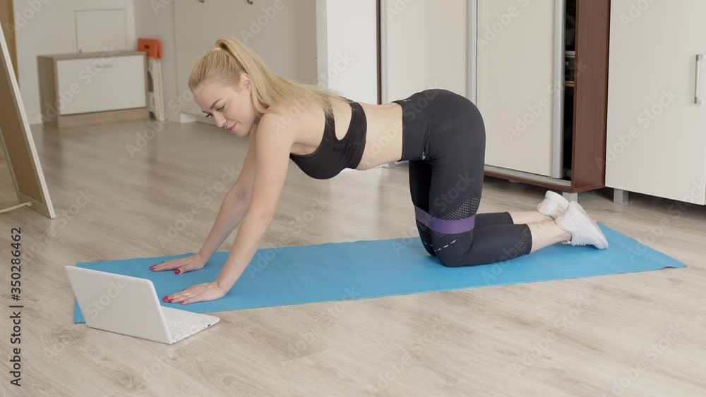Attractive sporty woman doing exercises at home while wathing online fitness lessons Attractive sporty woman doing exercises at home while wathing online fitness lessons