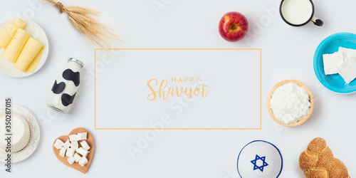 Jewish holiday Shavuot banner design with milk bottle, cheese and bread on white background. Top view from above