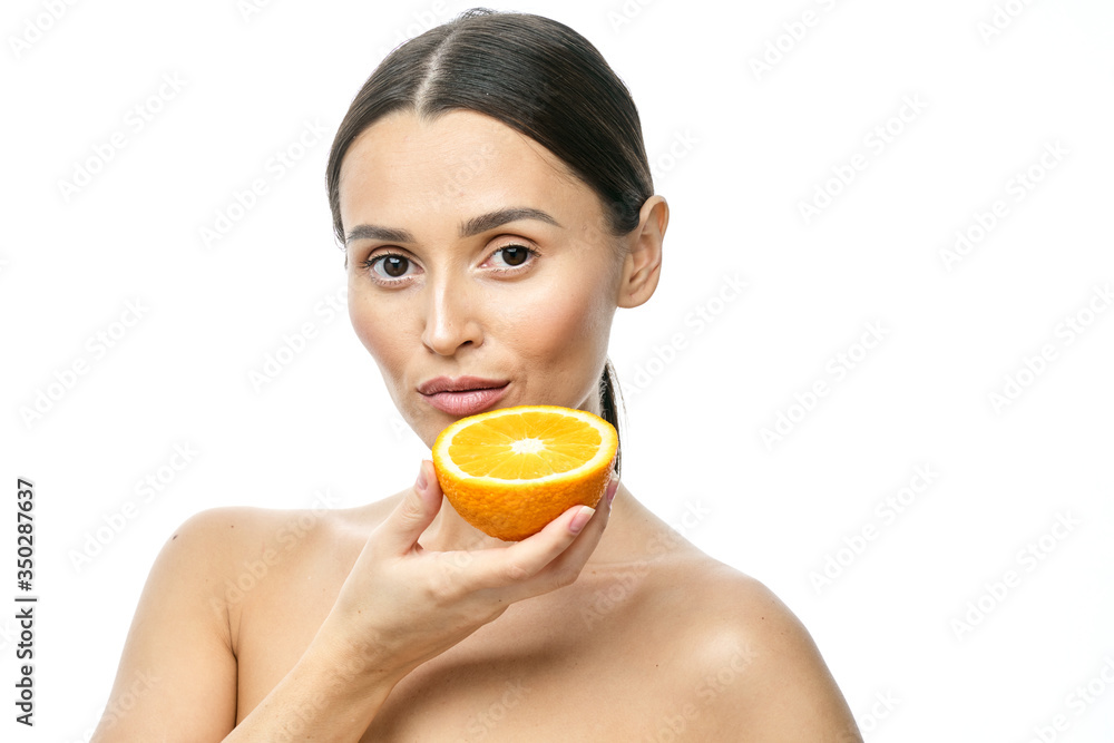 Close up beauty portrait of an excited attractive half naked woman holding orange slices at her face and looking at camera isolated over white background Close up beauty portrait of an excited attractive half naked woman holding orange slices at her face and looking at camera isolated over white background