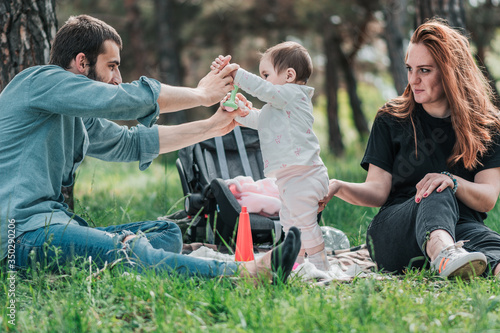 Family, child, childhood and parenthood concept - Happy little baby with parent learning to walk. Mother and Father support and help her. Outdoor, on picnic in forest. © A.P Photography