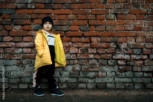 A girl poses against a brick wall. Young model.