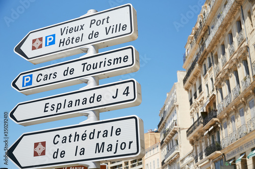 Black and white signs in French direct tourists to points of interest at the harbor in old world Marseille, France