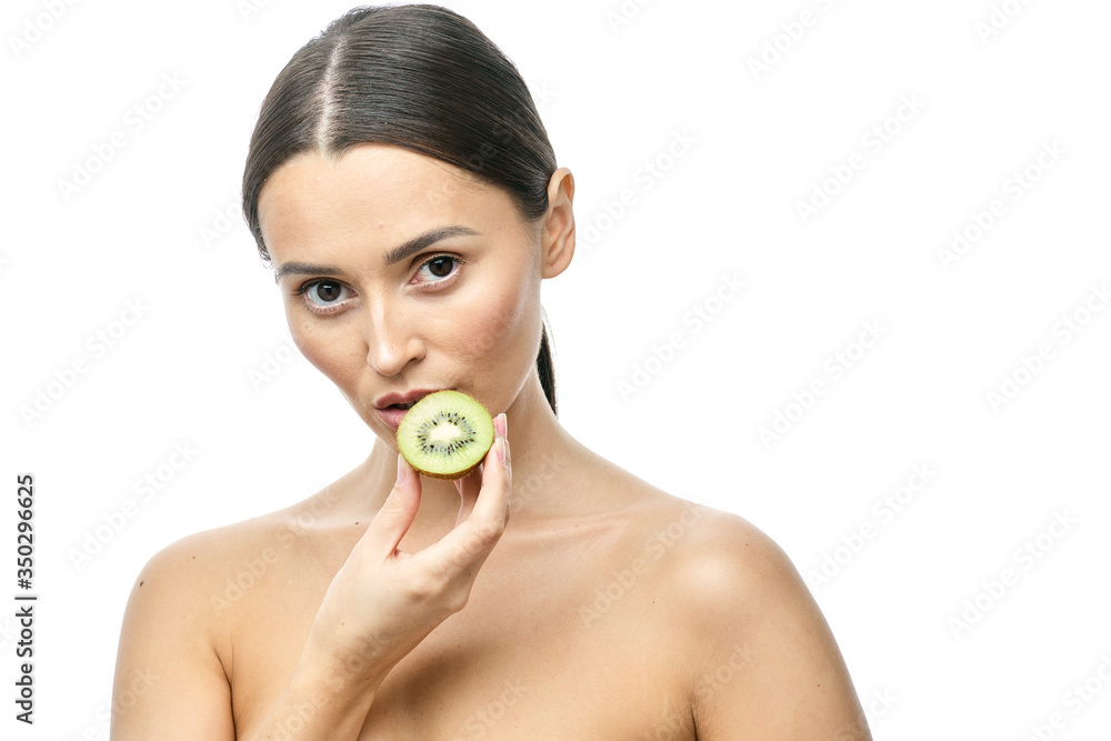 close-up portrait of a girl with clear skin holding a kiwi fruit to her face on a white background close-up portrait of a girl with clear skin holding a kiwi fruit to her face on a white background
