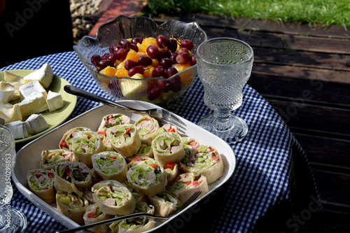 an empty glass, rolled up tortilla, fruit, cheese and wine on the terrace table