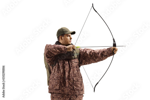 Man hunter in a camuflage uniform aiming with a bow and arrow