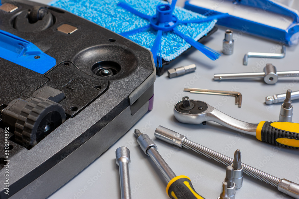 Fototapeta premium Robot vacuum cleaner. Vacuum cleaner robot repair on grey background with tools. Vacuum cleaner service.