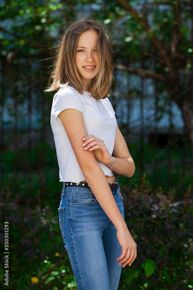 Portrait of a young blonde girl in white t-shirt and blue jeans Portrait of a young blonde girl in white t-shirt and blue jeans