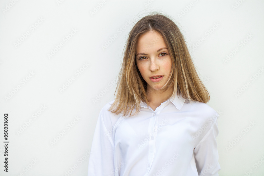 Young blonde girl in white blouse - isolated on white wall background Young blonde girl in white blouse - isolated on white wall background