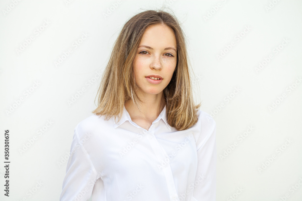 Young blonde girl in white blouse - isolated on white wall background Young blonde girl in white blouse - isolated on white wall background