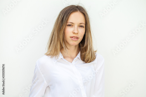 Young blonde girl in white blouse - isolated on white wall background