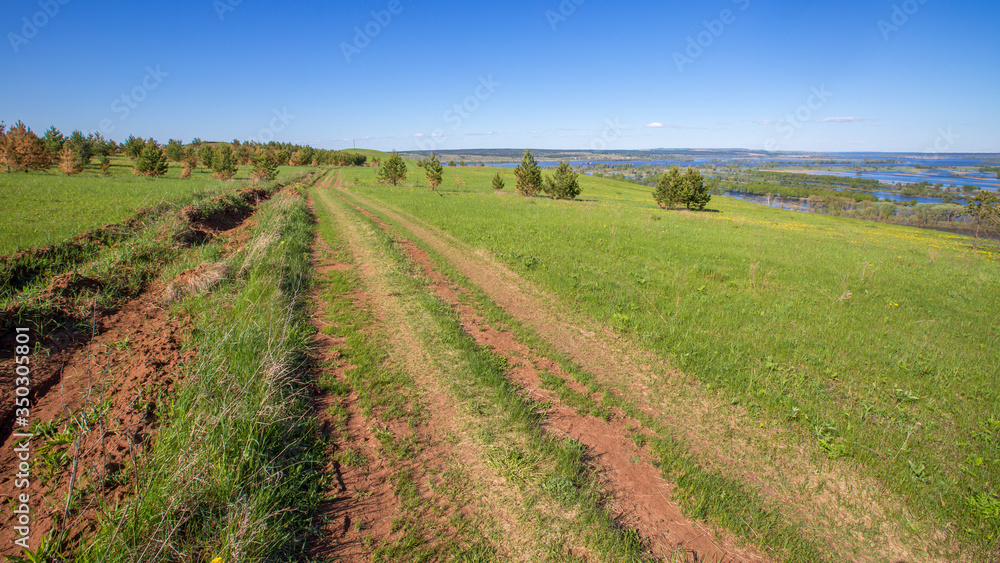 dirt road among meadows along the hillsides