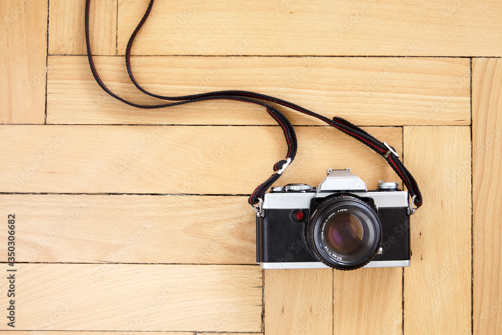 Old reflex camera with strap on the floor Old reflex camera with strap on the floor
