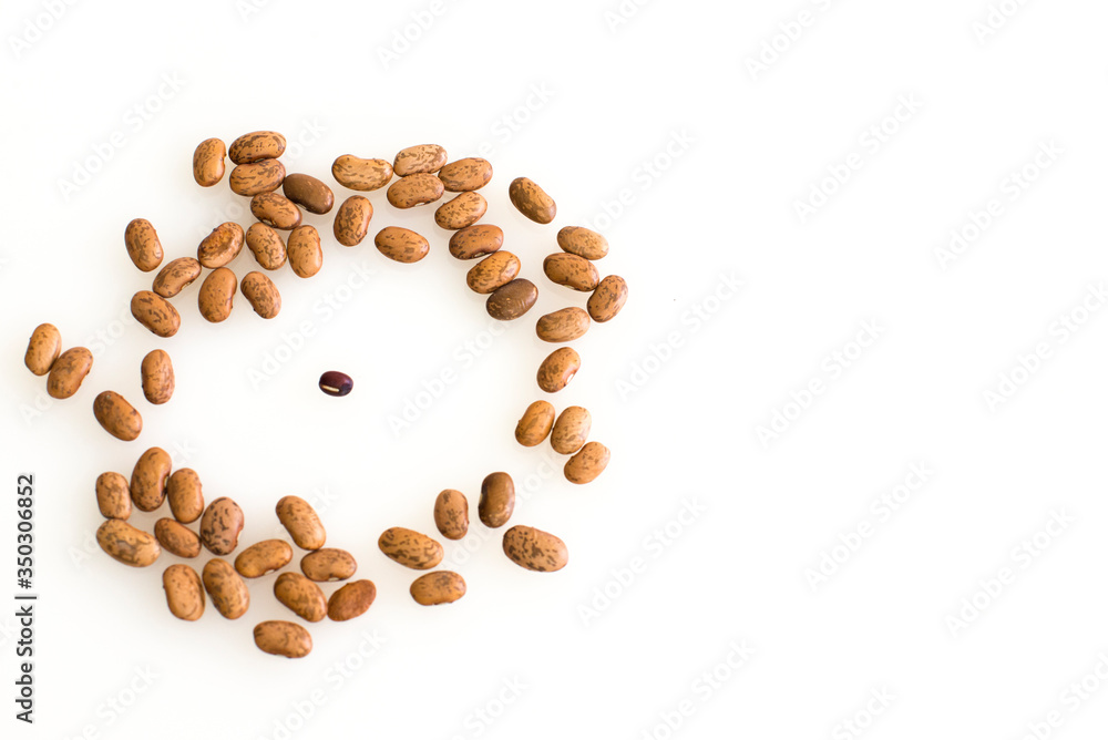 A large circle of bigger brown beans circle around a lone smaller bean in the middle, signifying bullying, bias, prejudice, prejudice, overtaking, jeering, enclosure or other intimidating act. A large circle of bigger brown beans circle around a lone smaller bean in the middle, signifying bullying, bias, prejudice, prejudice, overtaking, jeering, enclosure or other intimidating act.