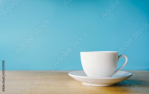 cup of coffee on wooden table with blue background 