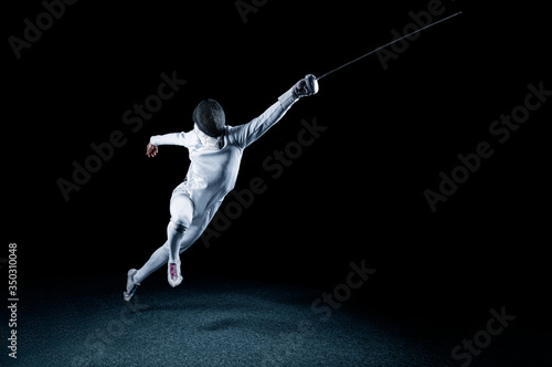 The fencer moves forward with a sword in his hand. Sport concept. photo