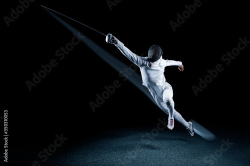 Fotografija The fencer moves forward with a sword in his hand. Sport concept.
