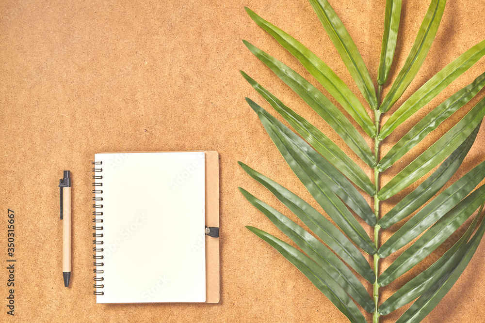 Pen, prepared to writing on mock up notebook in top view with tropical leaves. - obrazy, fototapety, plakaty 