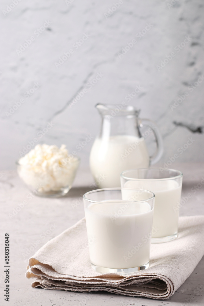 Kefir or Ayran fermented drink in two glasses, milk in jug and cottage cheese in a bowl on light gray background, Vertical format Kefir or Ayran fermented drink in two glasses, milk in jug and cottage cheese in a bowl on light gray background, Vertical format