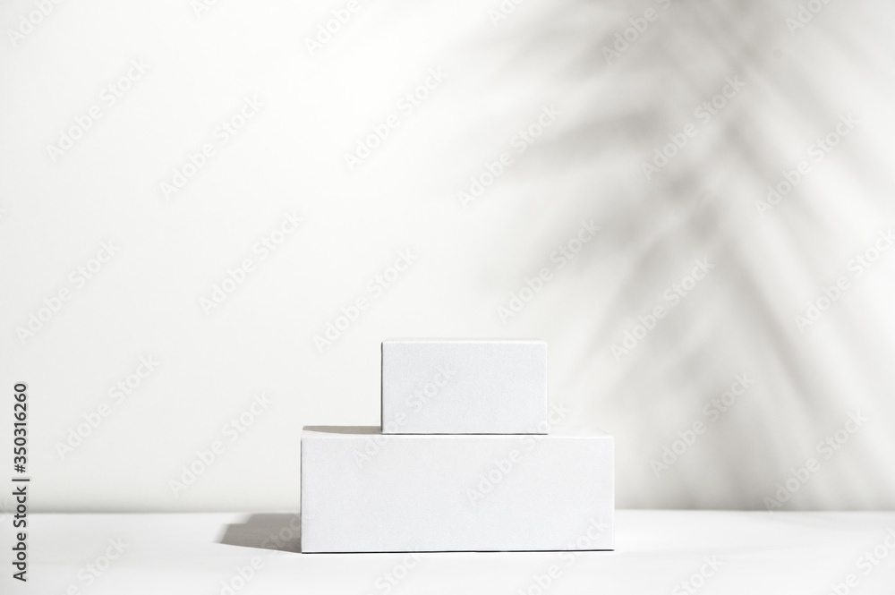 Fototapeta premium White empty stands on light shadow background. Blank unbranded shopfront. Showcase for cosmetic products. Product advertisement. Copy space. Cosmetology and beauty concept