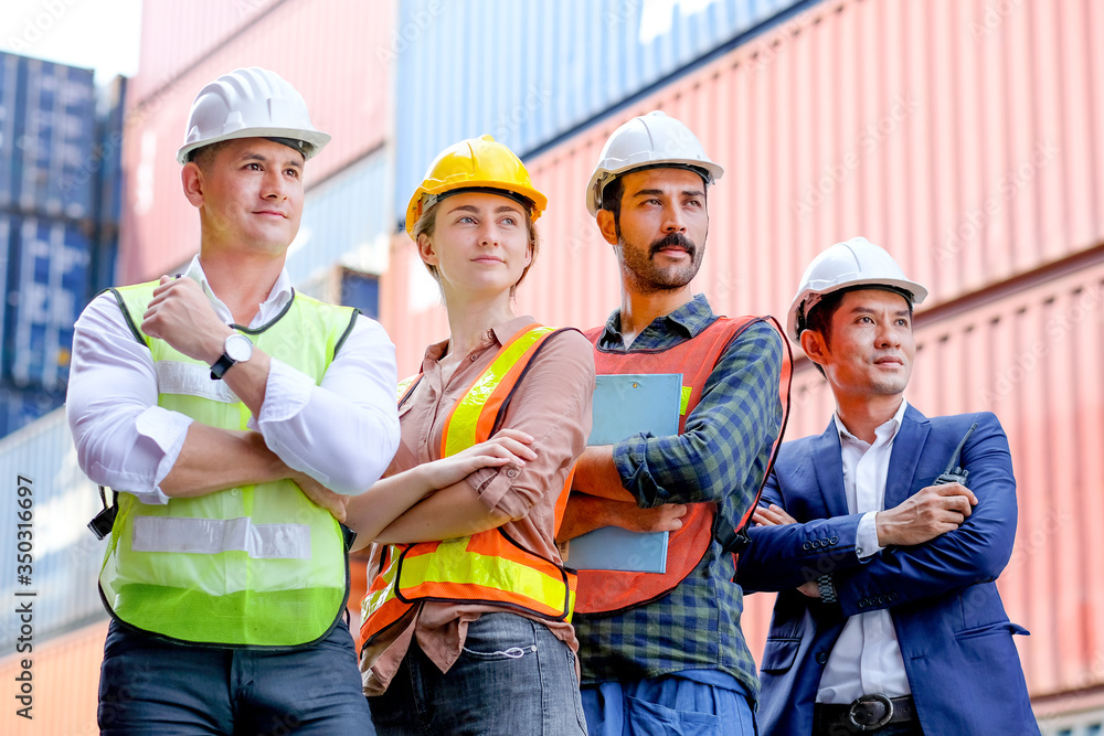 Group of technician or engineer worker stand with confident action or fold arms in cargo shipping workplace area. Concept with good teamwork system help to improve better industrial business. Group of technician or engineer worker stand with confident action or fold arms in cargo shipping workplace area. Concept with good teamwork system help to improve better industrial business.