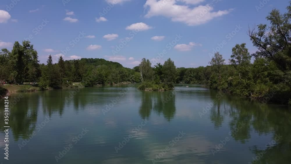drone shot over lake with green trees and blue sky drone shot over lake with green trees and blue sky