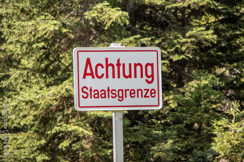View of a sign with the text in German, Attention State Border, in the European Alps on the Austrian Italian border