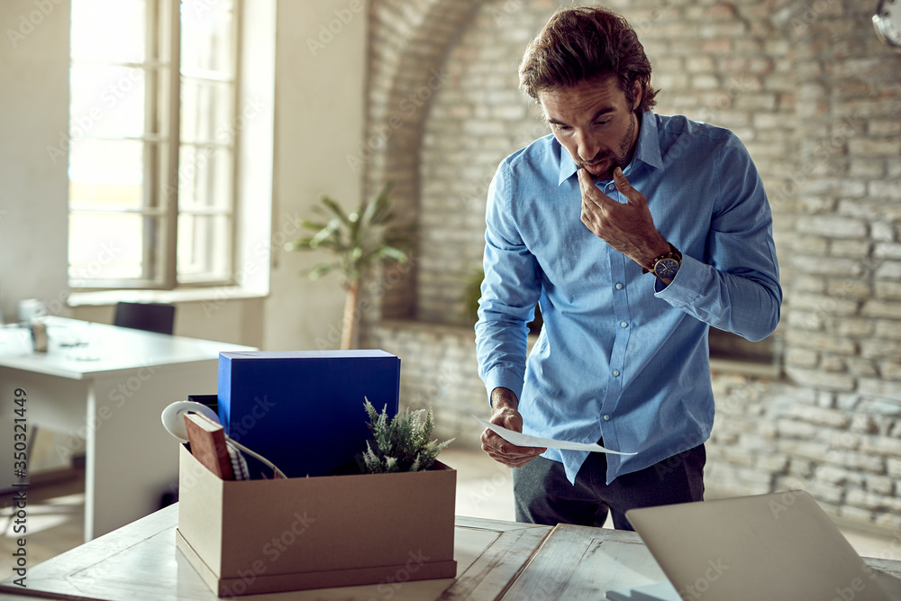 Shocked businessman reading a notice after being fired at work. Shocked businessman reading a notice after being fired at work.