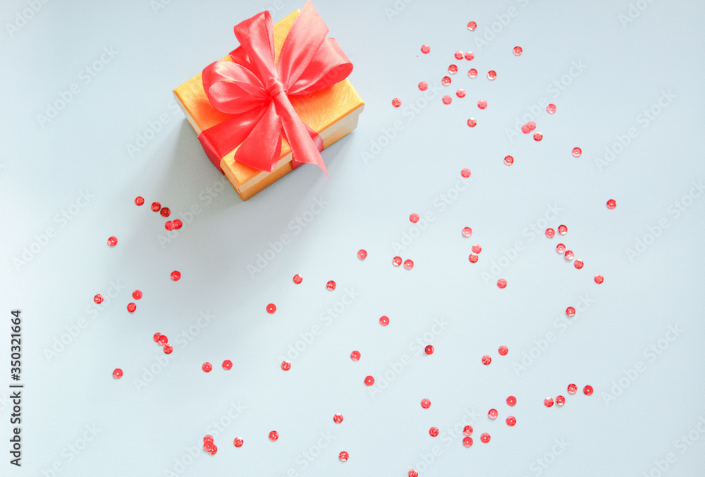 Yellow gift box with red bow and party confetti on a blue background. Flat lay Yellow gift box with red bow and party confetti on a blue background. Flat lay