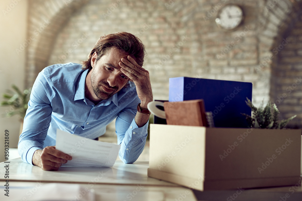 Obraz premium Displeased businessman reading a document after being fired in the office.